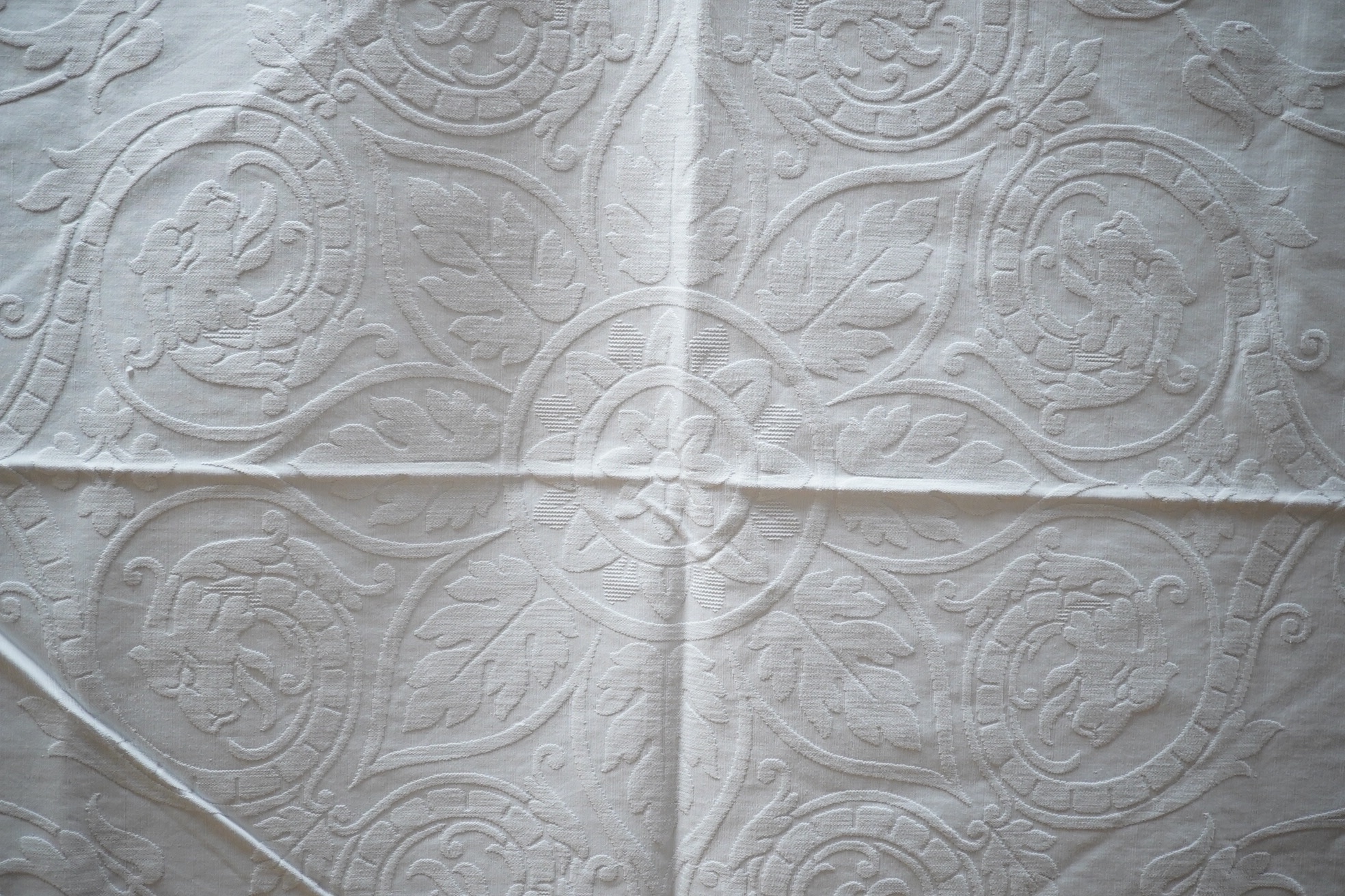 Three inspired Christopher Dresser white linen embossed bedcovers, with wide borders and ornate central designs, 216cm x 208cm. Condition - all good but will need rewashing.